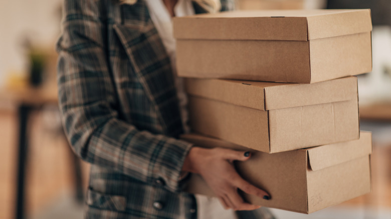 Woman holding brown cardboard shoeboxes